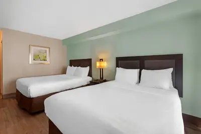 two beds in a hotel room with white sheets at Quality Inn & Suites 5585 Ambler Drive Mississauga Ontario in Mississauga