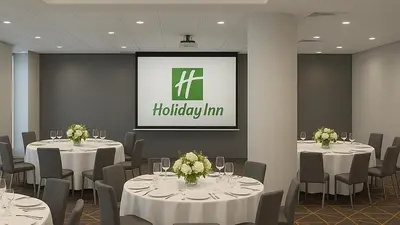 a conference room with white tables and chairs and a screen at Holiday Inn & Suites Mississauga West - Meadowvale by IHG in Mississauga