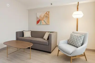 a living room with a couch and a chair and a table at Holiday Inn & Suites Mississauga West - Meadowvale by IHG in Mississauga