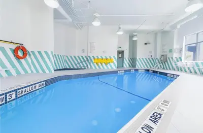 a large swimming pool in a white room with a blue pool at Holiday Inn & Suites Mississauga West - Meadowvale by IHG in Mississauga