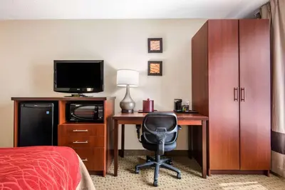 a hotel room with a desk with a television and a bed at Comfort Inn Airport West in Mississauga