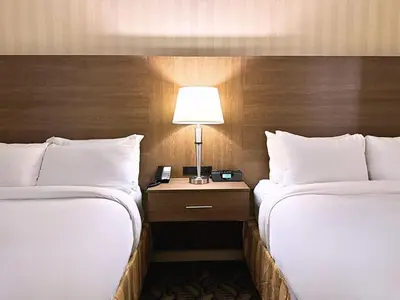two beds in a hotel room with a lamp on a table at Spencer Hotel & Conference Centre in London