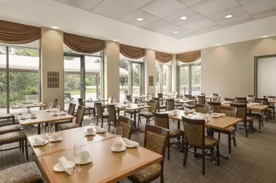 a dining room with tables and chairs and windows at Spencer Hotel & Conference Centre in London