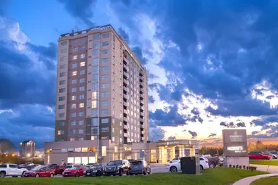 a tall building with cars parked in a parking lot at Sandman Signature Toronto Airport Hotel in Toronto