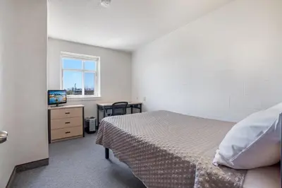 a bedroom with a bed and a desk with a television at Residence & Conference Centre - Welland in Welland