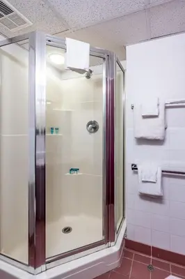 a shower in a bathroom with white towels at Residence & Conference Centre - Welland in Welland