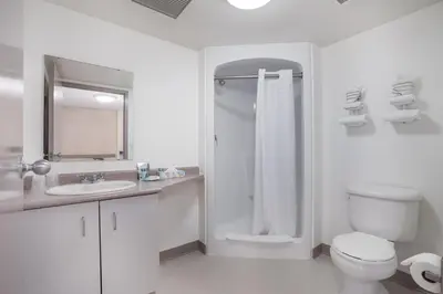 a white bathroom with a shower and a toilet at Residence & Conference Centre - Niagara-on-the-Lake in Niagara on the Lake