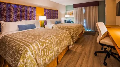 a hotel room with two beds and a desk at Best Western Premier Toronto Airport Carlingview Hotel in Toronto