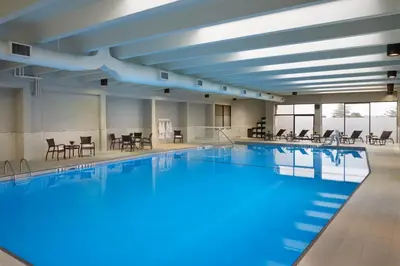 a large swimming pool with tables and chairs at Holiday Inn Toronto International Airport by IHG in Toronto