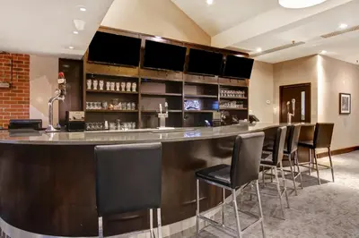 a bar with black bar stools in a room at Holiday Inn Oakville Centre by IHG in Oakville