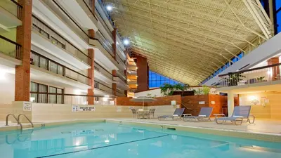 a swimming pool in a building with chairs and a ceiling at Holiday Inn Oakville Centre by IHG in Oakville