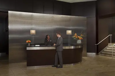 a man and a woman standing at a counter in a lobby at InterContinental Toronto Centre by IHG in Toronto