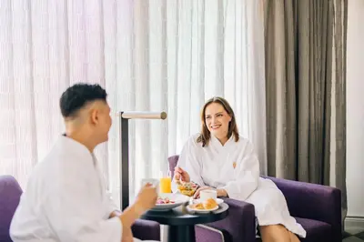 a man and a woman sitting in a purple chair eating food at InterContinental Toronto Centre by IHG in Toronto