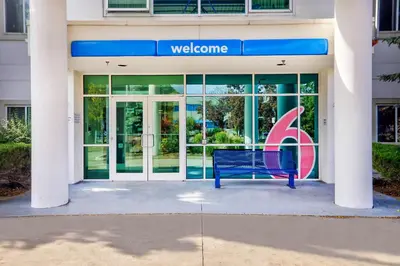 a blue bench in front of a building with a welcome sign at Motel 6-Burlington, ON - Toronto West - Oakville in Burlington