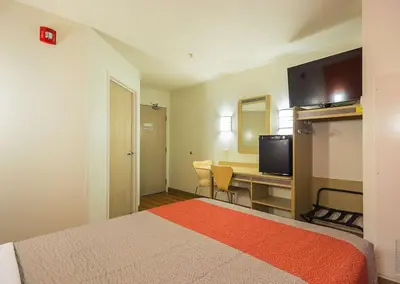 a hotel room with a bed and a desk with a television at Motel 6-Whitby, ON - Toronto East in Whitby