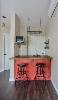 a kitchen with a wooden counter and two stools at The Village Suites in Wellington
