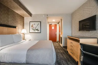 a hotel room with a bed and a flat screen tv at Monte Carlo Inn Barrie - Newly Renovated in Barrie