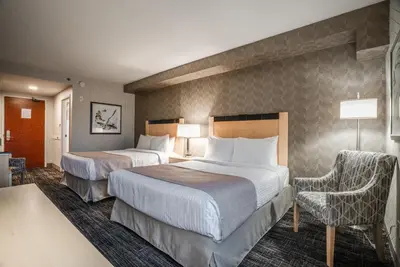 a hotel room with two beds and a chair at Monte Carlo Inn Barrie - Newly Renovated in Barrie