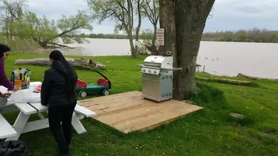 two women standing next to a picnic table next to a tree at Riverview Motel in Dunnville