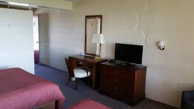a bedroom with a desk with a television and a bed at Riverview Motel in Dunnville