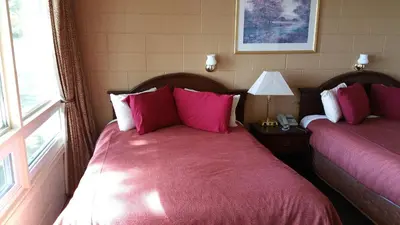 a bedroom with two beds with pink sheets and a window at Riverview Motel in Dunnville