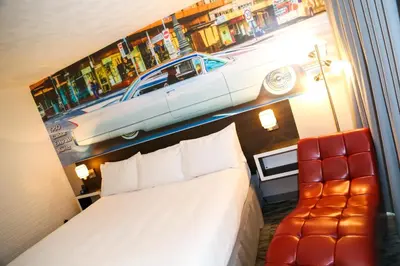 a bedroom with a bed and a car on the wall at Cadillac Motel Niagara in Niagara Falls