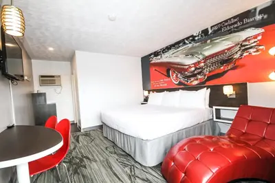 a hotel room with a bed and a red chair at Cadillac Motel Niagara in Niagara Falls