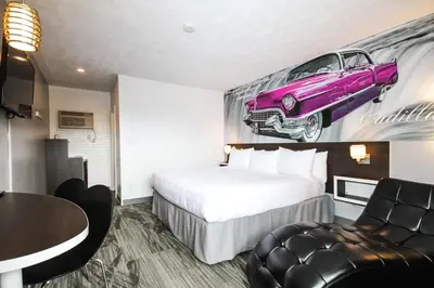 a hotel room with a bed and a purple car on the wall at Cadillac Motel Niagara in Niagara Falls