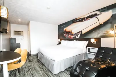 a hotel room with a bed and a car on the wall at Cadillac Motel Niagara in Niagara Falls