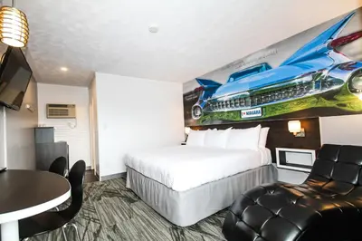 a hotel room with a bed and a car on the wall at Cadillac Motel Niagara in Niagara Falls