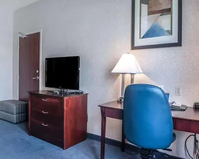 a room with a desk with a television and a blue chair at Comfort Inn in Mississauga