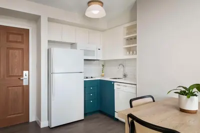 a white kitchen with a table and a refrigerator at Sonesta ES Suites Toronto Markham in Markham