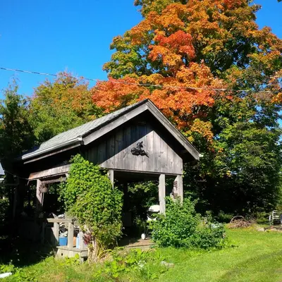 an old barn with colorful trees in the background at Picturesque School House Retreat in Meaford