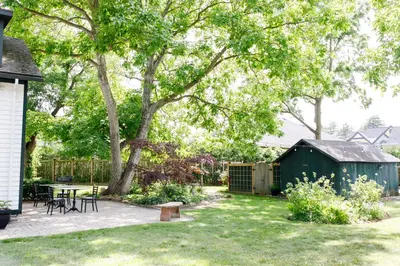 a backyard with a tree and a table and chairs at Woodbourne Inn in Niagara on the Lake