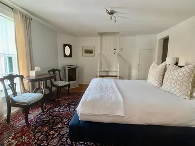 a bedroom with a large bed and a table and chairs at Woodbourne Inn in Niagara on the Lake