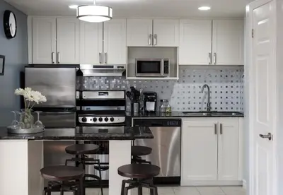 a kitchen with white cabinets and stainless steel appliances at Mountain Side Studio at The Blue Mountains in Blue Mountains