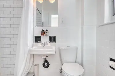 a white bathroom with a toilet and a sink at The Windsor Hotel by Hoco Hotels Collection in Stratford