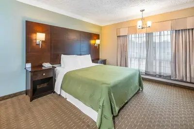 a hotel room with a bed with a green blanket on it at Rodeway Inn Festival in Stratford