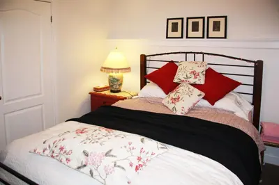 a bedroom with a bed with red and white pillows at 2 Moon Cottage in Niagara on the Lake