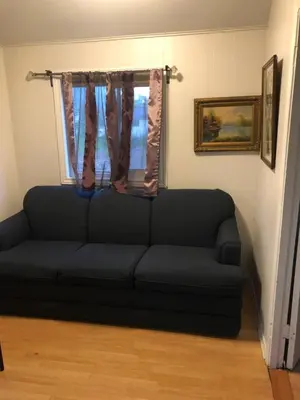 a black couch in a living room with a window at Wasaga Bridge Cottages in Wasaga Beach