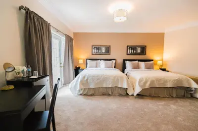 a bedroom with two beds and a desk and a window at Newton Villa in Brampton