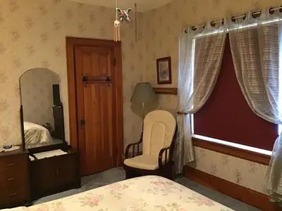 a bedroom with a bed and a mirror and a chair at 10th Avenue Guest House & Suites in Hanover