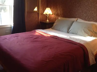 a bed with a red blanket on it in a bedroom at 10th Avenue Guest House & Suites in Hanover