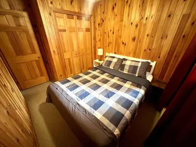 a bedroom with a bed with a blue and white checkered blanket at High Falls Bay Cottages, Camping & Waterpark in Bracebridge