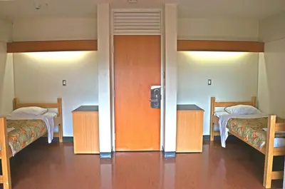 a room with two beds and two tables and a door at University of Toronto - New College Residence - Wilson Hall Residence in Toronto