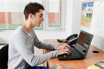 a man sitting at a desk using a laptop computer at University of Toronto-New College Residence-45 Willcocks Residence in Toronto