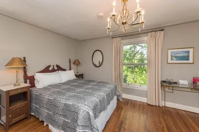 a bedroom with a bed and a window and a chandelier at The Old Bank House in Niagara on the Lake