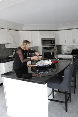 a woman standing in a kitchen preparing food at Molly's Retreat B and B in Orangeville