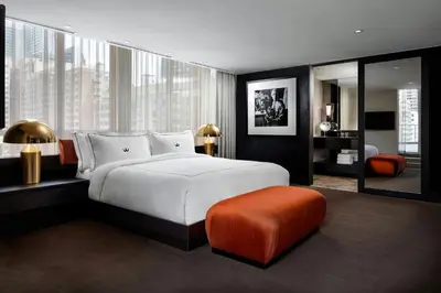 a bedroom with a large white bed and an orange ottoman at BISHA, a Luxury Collection Hotel, Toronto in Toronto