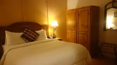 a bedroom with a white bed with a lamp and a cabinet at Benmiller Inn & Spa in Goderich